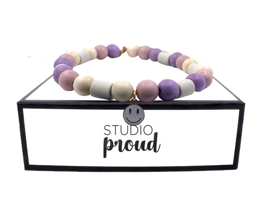 Anti-tick collar La Rochelle with lilac beads and floral charm on a display.